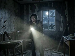 A frightened person clutches a flashlight inside a dark, decaying wooden cabin, the beam cutting through thick dust and illuminating peeling wallpaper and broken furniture. A single cracked window lets in pale moonlight from outside. Style: atmospheric horror film still. Mood: tense and unsettling.